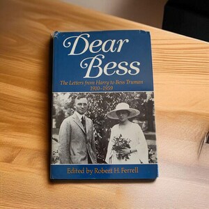 Könnte beinhalten: Ein Buch mit dem Titel "Dear Bess" mit blauem Einband. Das Buch zeigt ein Schwarz-Weiß-Foto eines Mannes und einer Frau. Der Text auf dem Einband lautet "The Letters from Harry to Bess Truman 1910-1959" und "Edited by Robert H. Ferrell."