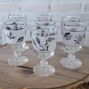 May include: Set of eight clear glass wine glasses with frosted white bases and silver leaf designs of leaves and flowers.