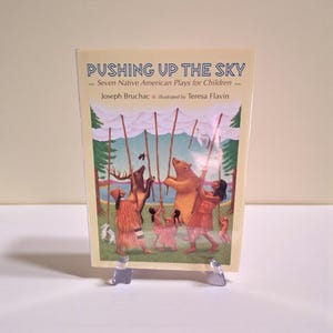 Puede incluir: Un libro infantil titulado "PUSHING UP THE SKY" con ilustraciones de figuras y animales nativos americanos. La portada representa un oso, un ciervo y personas sosteniendo postes. El autor es Joseph Bruchac y la ilustradora es Teresa Flavin.