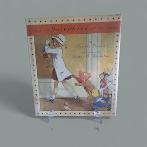 Pode incluir: Capa de livro infantil vintage intitulada "A Day with Josephine and Her Friends". A ilustração mostra uma menina com um cão e outros personagens. A autora é Pamela Prince e a ilustradora é Honor C. Appleton.