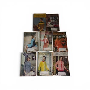 May include: A collection of eight vintage Workbasket and Home Arts magazines arranged in three rows. Each magazine cover features a different person modeling various knitted or crocheted garments, including sweaters, cardigans, and a poncho.