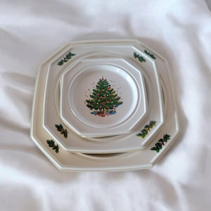 Könnte beinhalten: Ein Set aus drei weißen Keramiktellern mit einem grünen und weißen Weihnachtsbaumdesign. Die Teller sind achteckig und haben einen erhöhten Rand.