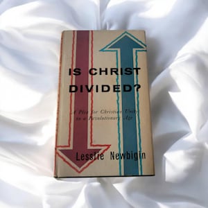 Puede incluir: Un libro titulado "Is Christ Divided? A Plea for Christian Unity in a Revolutionary Age" de Lesslie Newbigin. La portada presenta dos flechas apuntando en direcciones opuestas, una roja y otra azul.