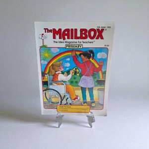 May include: The cover of "The MAILBOX" magazine, featuring a colorful illustration of two children, one in a wheelchair, painting a rainbow. The magazine's title and issue details are displayed at the top, with the word "PRIMARY" in a green box.