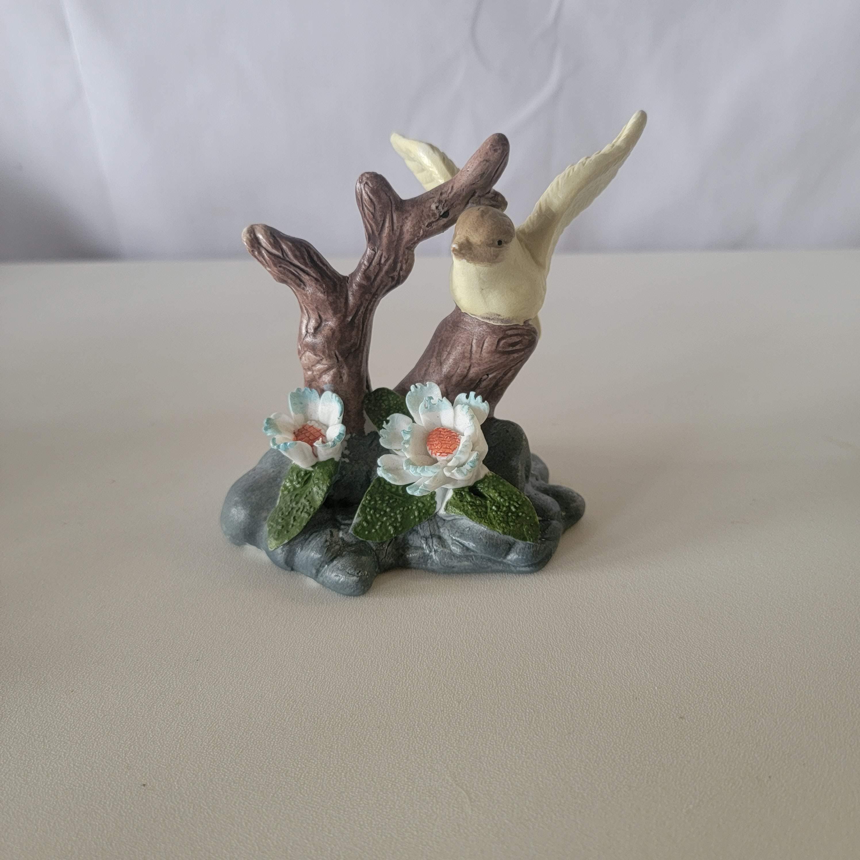 3Dの青と白の花が付いた小さな磁器の鳥の置物、木の枝と岩の上にいる