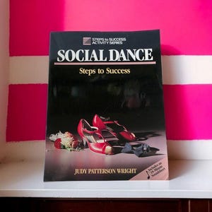 May include: A book titled "SOCIAL DANCE Steps to Success" with red high heels and flowers on the cover. The book is part of the "STEPS to SUCCESS ACTIVITY SERIES" and includes a soundsheet. The author's name, JUDY PATTERSON WRIGHT, is also visible.
