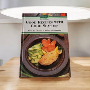 May include: A vintage cookbook titled "Good Recipes with Good Seasons" from the kitchens of Kraft General Foods. The cover features a photo of a plated meal with zucchini, carrots, and a chicken breast.