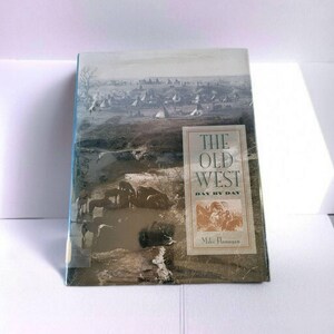 May include: A hardcover book titled "The Old West Day by Day" with a sepia-toned cover illustration of a historical scene. The cover features a landscape with teepees, horses, and the book's title in a rectangular box.