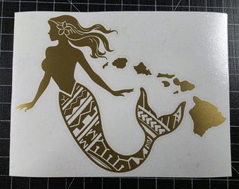 Könnte beinhalten: Ein goldfarbener Vinyl-Aufkleber mit der Silhouette einer Meerjungfrau mit einer Blume im Haar und einem gemusterten Schwanz, neben einer Reihe von Formen, die die hawaiianischen Inseln darstellen, auf einem weißen Trägerpapier.