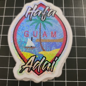 May include: Holographic sticker with a design featuring a palm tree, sailboat, and the words "Hafa Guam Adai." The sticker has a red and white border and a shimmering, iridescent finish.