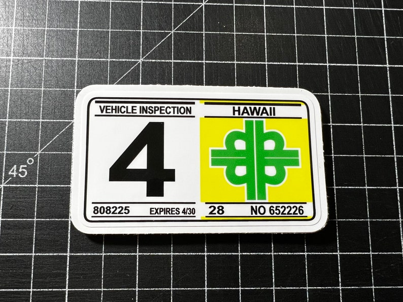 May include: White sticker with black text "VEHICLE INSPECTION" and a large black number "4". Below the number is "808225 EXPIRES 4/30". On the right side of the sticker is a yellow square with green text "HAWAII" and a green symbol. Below the symbol is "28 NO 652226".