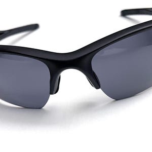 May include: Black sunglasses with gray lenses. The sunglasses have a sleek, modern design with a curved frame and a semi-rimless style. The lenses are a dark gray color, providing protection from the sun.