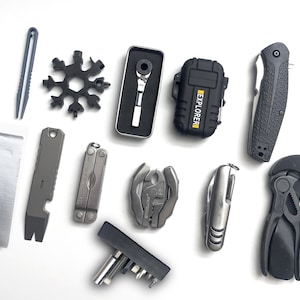 May include: A collection of multi-tools and survival gear including a snowflake-shaped wrench, a ratchet in a case, a black lighter labeled EXPLORER, a folding knife, a pry bar, a silver multi-tool, pliers, a bit driver set, and duct tape.