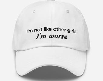 Könnte beinhalten: Weiße Baseballkappe mit dem schwarzen Text "I'm not like other girls, I'm worse". Die Kappe hat einen gebogenen Schirm und einen Knopf oben. Ein lässiges Accessoire.