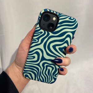 May include: A green and blue phone case with a wavy abstract pattern. The case has a black camera cutout.