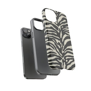 K&ouml;nnte beinhalten: Eine Handyh&uuml;lle mit Zebra-Muster in Schwarz und Wei&szlig; f&uuml;r ein iPhone. Die H&uuml;lle wird mit einem schwarzen Telefon gezeigt.