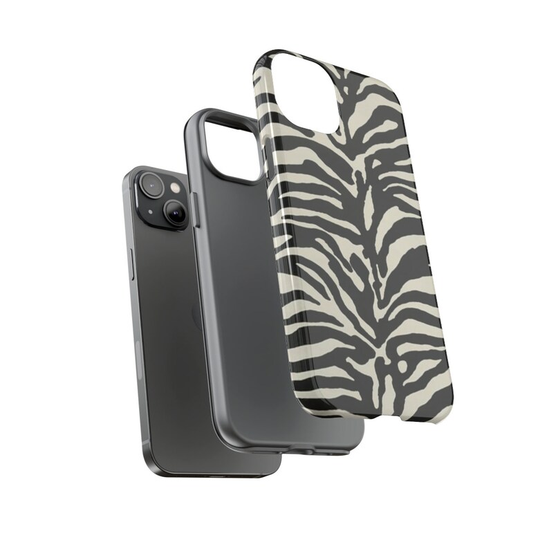 K&ouml;nnte beinhalten: Eine Handyh&uuml;lle mit Zebra-Muster in Schwarz und Wei&szlig; f&uuml;r ein iPhone. Die H&uuml;lle wird mit einem schwarzen Telefon gezeigt.