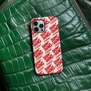 May include: White iPhone case with a repeating pattern of red "DUM DUMS CHERRY" text.