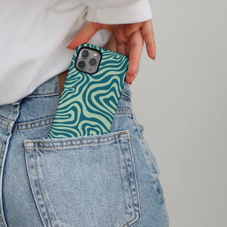 May include: A green and light green phone case with a wavy pattern. The case is in a back pocket of blue jeans. GRACIE Groovy Protective | Trendy | Cute | Aesthetic | Stylish | Sleek | Chic | iphone case | iphone