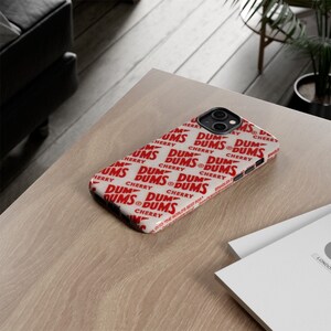 May include: A white iPhone case with a repeating pattern of red "DUM DUMS CHERRY" text.
