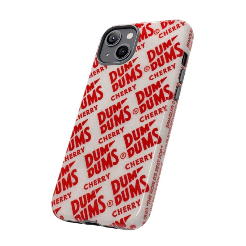 May include: A white iPhone case with a red and white pattern of "DUM DUMS CHERRY" repeated across the surface. The case has a black camera bump with two lenses.