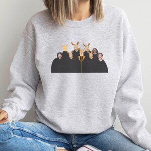 May include: A gray sweatshirt with a graphic print of a group of people with kangaroo heads. The people are wearing black robes and are standing in a row.