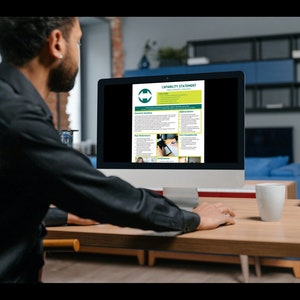 A man editing the capability statement template in Canva on his desktop computer.