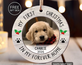 May include: A round, wooden Christmas ornament with a photo of a golden retriever puppy wearing a red and black plaid bandana. The ornament has the text "MY FIRST CHRISTMAS IN MY FOREVER HOME" and the name "CHARLIE" with the year "2026". Includes paw prints and holly.