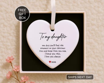 May include: A white heart-shaped ornament with a ribbon for hanging, presented in a gift box. The ornament has the text "To my daughter" and a loving message from "mom". A red heart symbol is included.