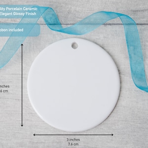 Peut inclure: Un ornement rond en c&eacute;ramique de porcelaine blanche avec une finition brillante et un petit trou en haut pour le suspendre. L'ornement mesure 7,6 cm sur 7,6 cm. Un ruban bleu clair est inclus avec l'ornement pour la pr&eacute;sentation.