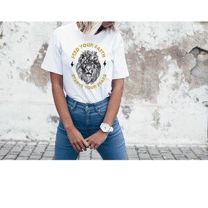 May include: White t-shirt with a graphic of a lion's head and the text "Feed Your Faith Starve Your Fears".