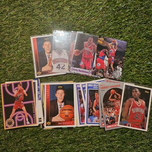 Puede incluir: Una colección de tarjetas de intercambio de baloncesto con jugadores de los Philadelphia 76ers y otros equipos. Las tarjetas son de varios colores, incluyendo rojo, blanco, azul y dorado. Las tarjetas muestran los nombres de los jugadores, los logotipos de los equipos y las estadísticas de los jugadores.