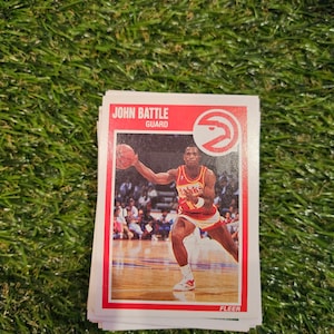 Puede incluir: Una pila de cromos de baloncesto con John Battle, un escolta de los Atlanta Hawks. Las tarjetas tienen un borde rojo e incluyen el logotipo de los Hawks y el logotipo de Fleer.