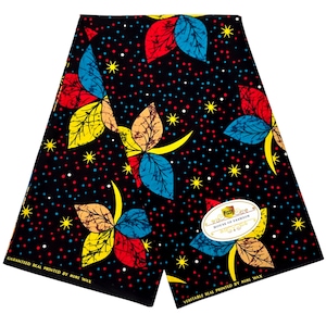 May include: A black fabric featuring a repeating pattern of multi-colored leaves in red, blue, and yellow, accented by small white and red dots and yellow stars. A white oval label reads Pizzy House of Fashion, and text reads Guaranteed Real Printed by Mimi Wax.