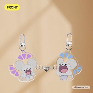 Op de afbeelding: Twee doorzichtige acryl sleutelhangers met cartoonmuizen, verbonden door een zilveren ketting met een hartvormige bedel. Elke muis heeft een wit lichaam, grijze oren en is omgeven door een decoratief ontwerp in paars en blauw. Het woord "FRONT" staat in geel.