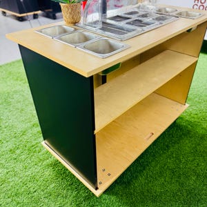 May include: A wooden food prep station with a black base and two shelves. The top surface has multiple stainless steel bowls and a clear plastic lid.