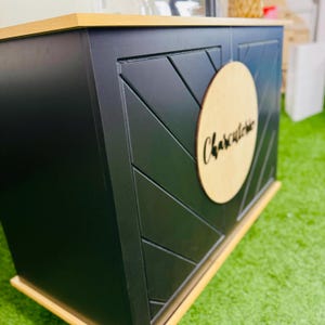 May include: A black wooden serving bar with a wood top and a round wooden sign that says "Charcuterie".