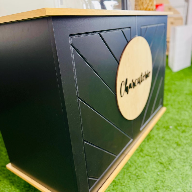 May include: A black wooden serving bar with a wood top and a round wooden sign that says "Charcuterie".