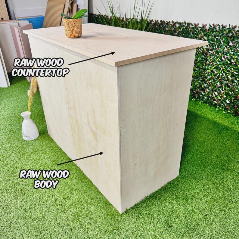 May include: A raw wood countertop and body, with the text "RAW WOOD COUNTERTOP" and "RAW WOOD BODY" in the image. The light-coloured wood has a natural grain. A small woven basket with a plant sits on top of the countertop.