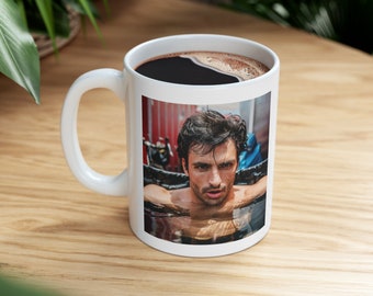 May include: White ceramic mug with a photo of a man with dark hair and a beard, submerged in water. The man is looking directly at the camera.