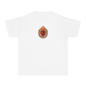 May include: White t-shirt featuring a graphic of a red heart with a crown of thorns and flames on the front.