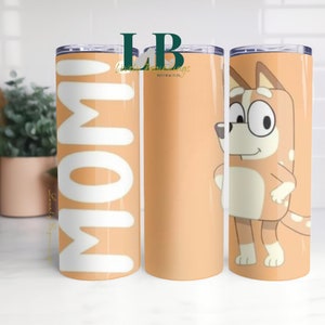 May include: Three stainless steel tumblers with different designs. The first tumbler has the word "MOM" in white letters on an orange background. The second tumbler has a light orange background with the text "LB Lovely Blessings Matthew 11:28". The third tumbler has a cartoon image of a brown and white dog with glasses on an orange background.