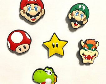 May include: Set of six colorful cartoon character charms, including Mario, Luigi, a star, a mushroom, a turtle, and a Bowser. The charms are made of rubber and are perfect for adding a fun touch to backpacks, keychains, or other accessories.