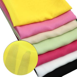 May include: A stack of colorful, sheer fabric squares in shades of yellow, pink, cream, green, red, white, and black. A close-up shows the fine weave of the yellow fabric. The fabrics appear lightweight and suitable for various craft projects.