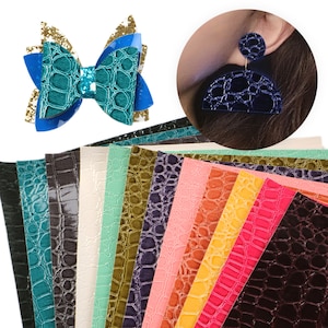 May include: A set of 12 faux leather sheets with a crocodile embossed pattern in various colours, including teal, green, brown, purple, pink, orange, yellow, red, and burgundy. The sheets are ideal for crafting projects such as earrings, hair bows, and other accessories.
