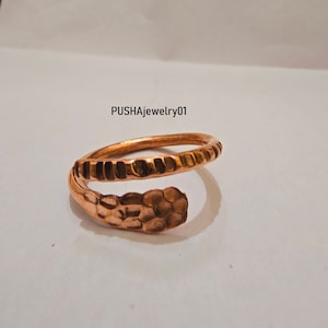 Peut inclure: Une bague en cuivre avec un design texturé. La bague est enroulée sur elle-même, créant un look unique et moderne.  PUSHAjewelry01