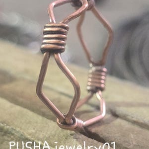 Pode incluir: Um anel de fio de cobre com forma hexagonal. O fio é torcido e enrolado para criar um design único.
