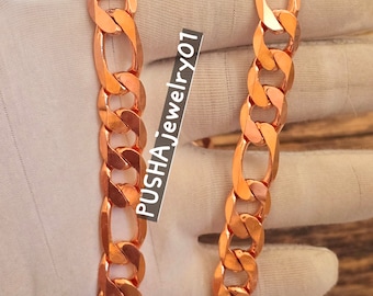 May include: A copper chain necklace with a curb link design. The chain is thick and has a shiny finish.