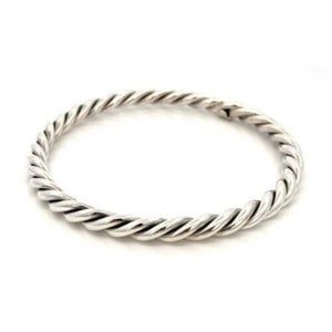 Puede incluir: Un brazalete de plata trenzado. El brazalete está hecho de una sola pieza de metal trenzado y tiene un acabado liso y pulido.