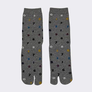 May include: A pair of gray tabi socks with a split toe design. The socks feature a pattern of colorful numbers.